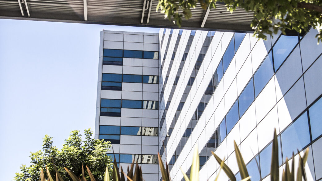 A view of the Garland Datacenter, with plants and trees in the foreground, showcasing its impact on the environment and its relevance to the public sector.