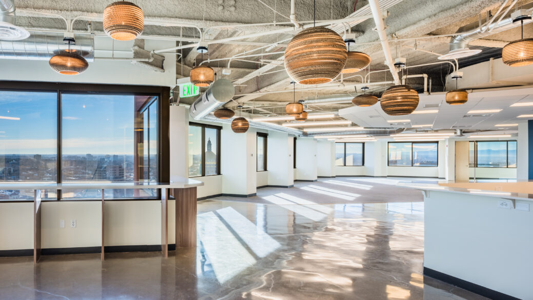 An interior photo of an empty office space in Denver's Civic Center Plaza with the skyline visible through the windows.