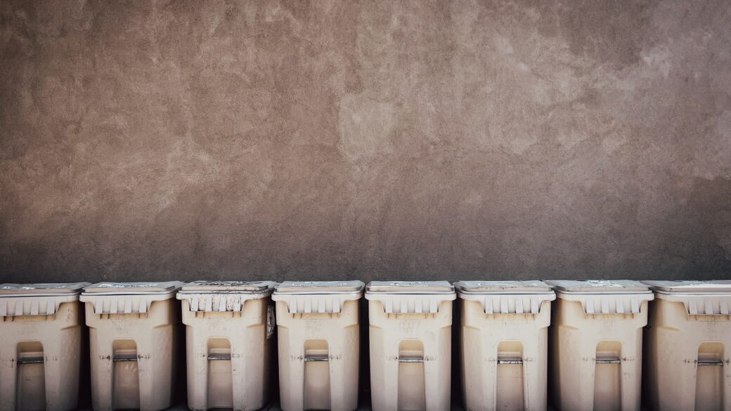 A row of trash bins lined up on the side of a building