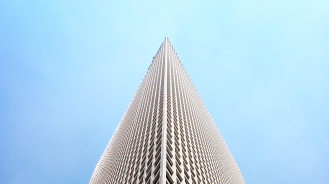 Corner perspective photo of a tall building from the ground looking up towards the sky