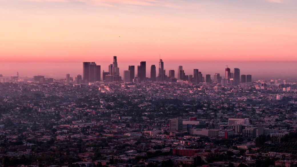 A breathtaking panoramic cityscape of DTLA rising silhouetted against a vibrant sunset, creating an unforgettable urban skyline.