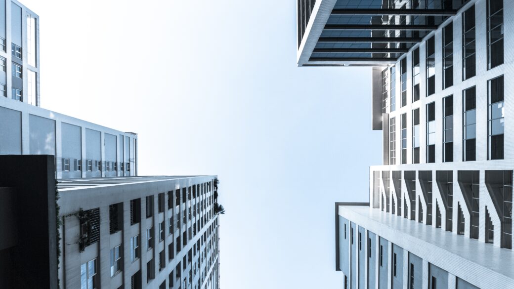 Ground view photo looking straight up into the sky with multi-tenant/apartment buildings rising up on the right and the left.