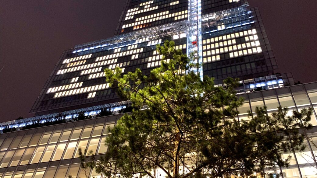 Street level photo looking straight up at an office building with the night sky in the background